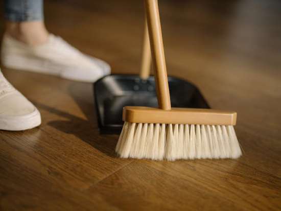 A person sweeping dust and dirt into a dustpan