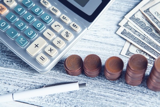  A calculator next to stacks of coins and cash